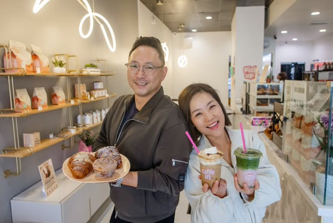 The owners of Caffe In Coffee, behind the counter with pastries and cream top lattes